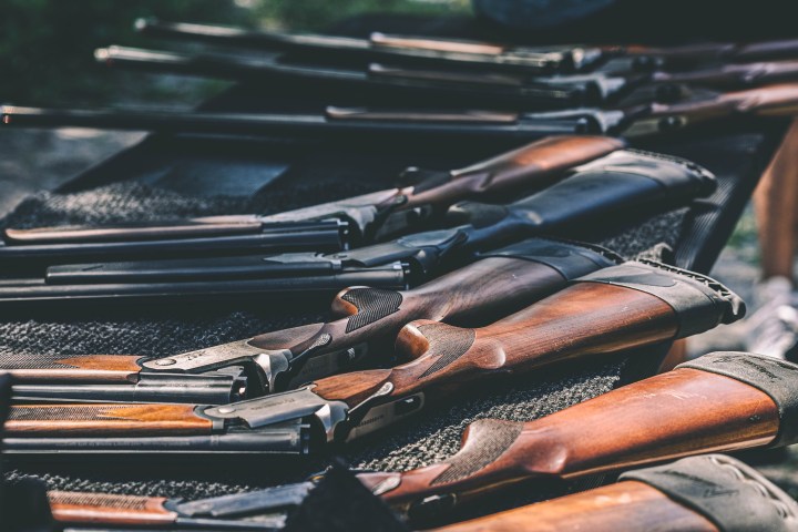 Long guns with wooden stocks lined on a table.