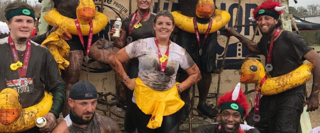 Muddy team posing with rubber ducks after an obstacle course race.